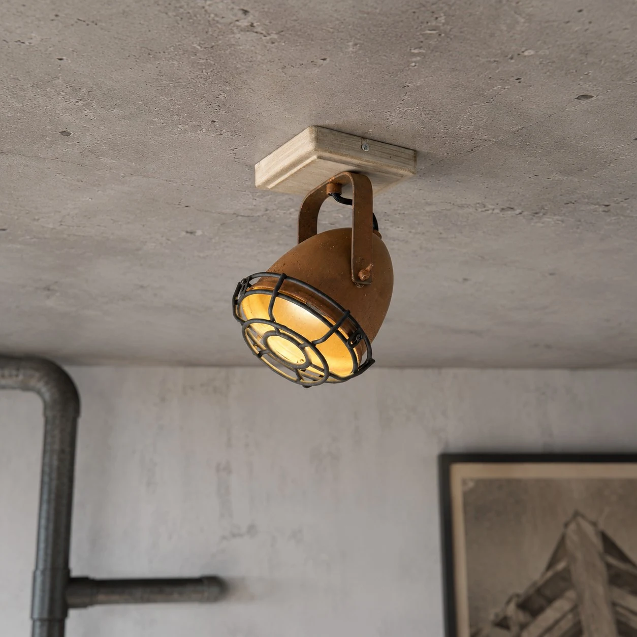 Rust adjustable ceiling spotlight casting a warm GU10 beam
